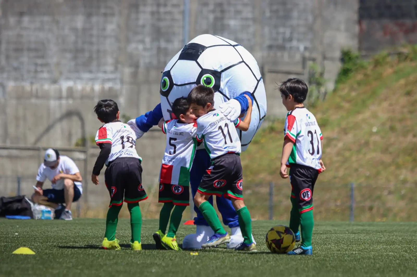 Niños jugando con una mascota con forma de balón durante Promesas Cup