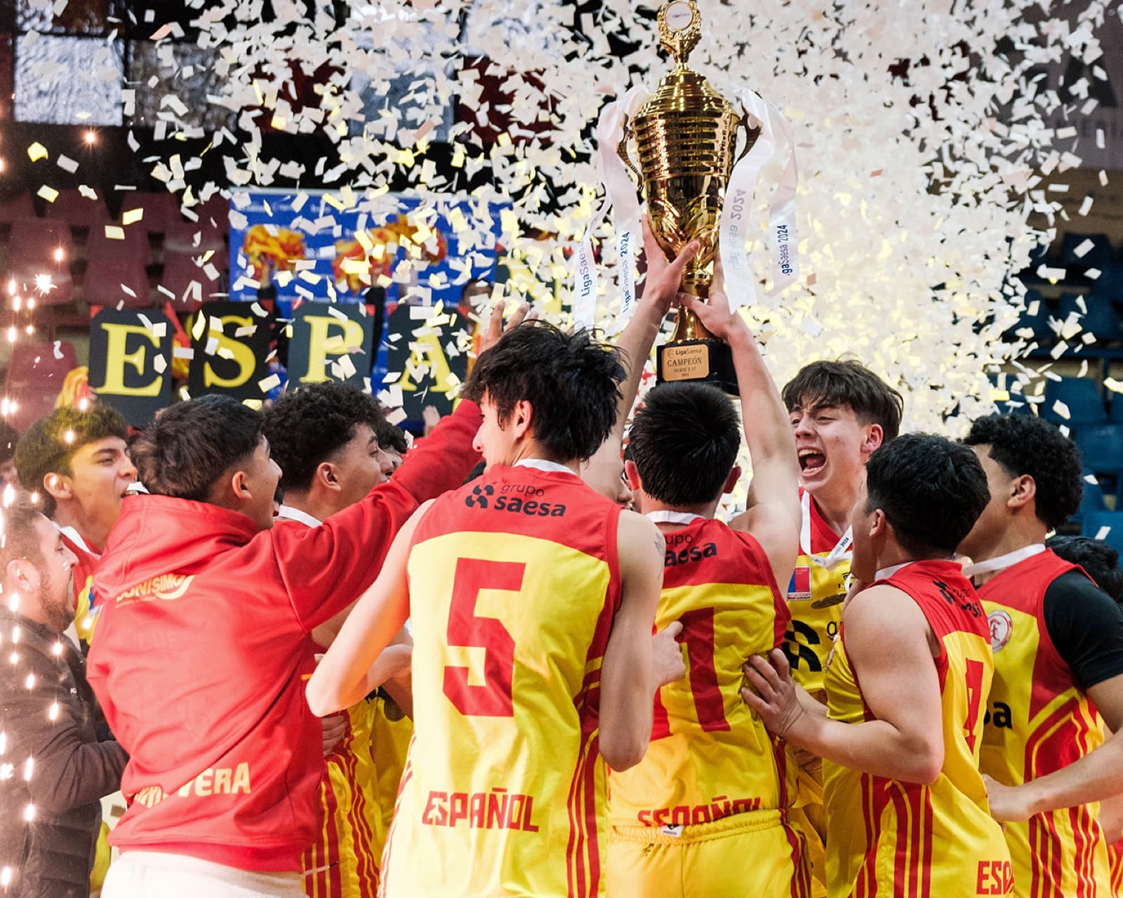 Jugadores de básquetbol levantando el trofeo bajo el confeti